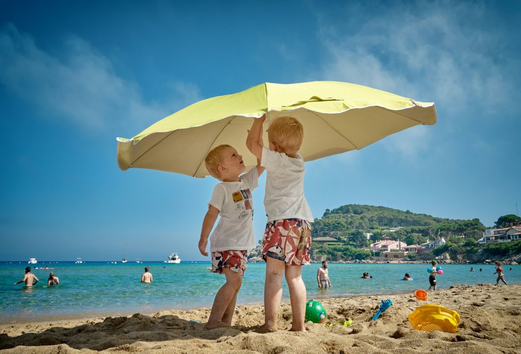 Two kids putting up an umbrella on the beach