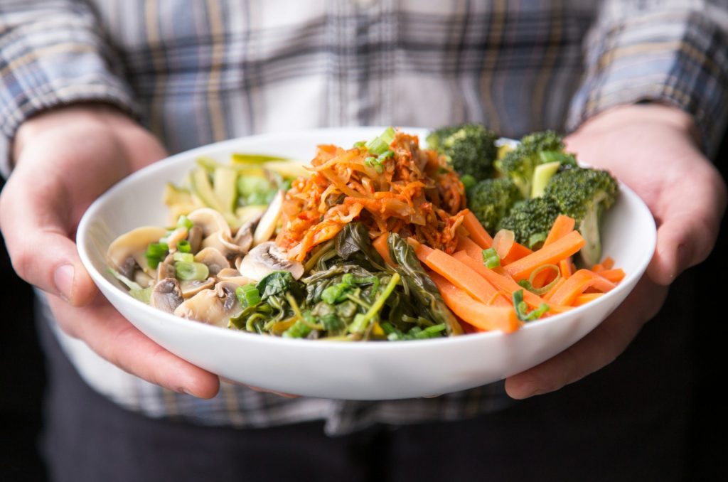 Person holding a vegan bowl of vegetables